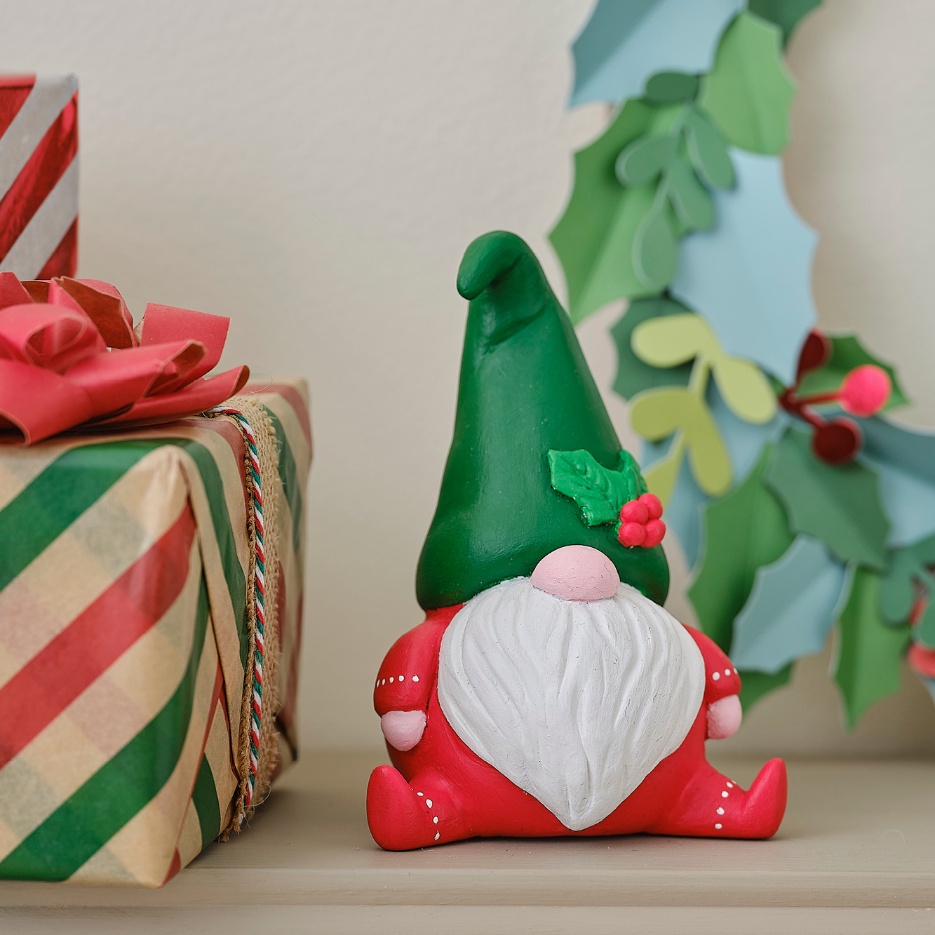 A christmas gnome made from air dry clay on a shelf surrounded by presents and a paper wreath. Clicking leads to all ideas and projects